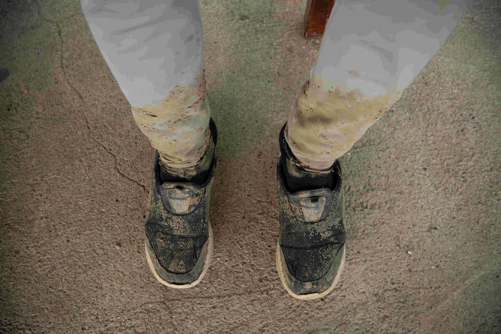 A migrant wearing muddy shoes