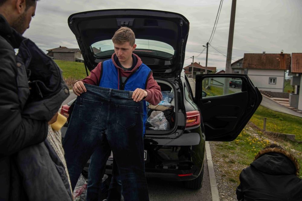 A volunteer hands a pair of jeans to a migrant