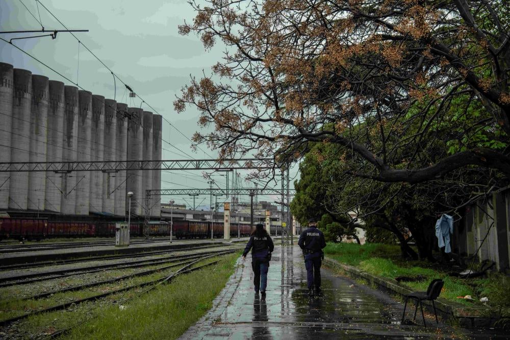Two police officers walk next to train tracks