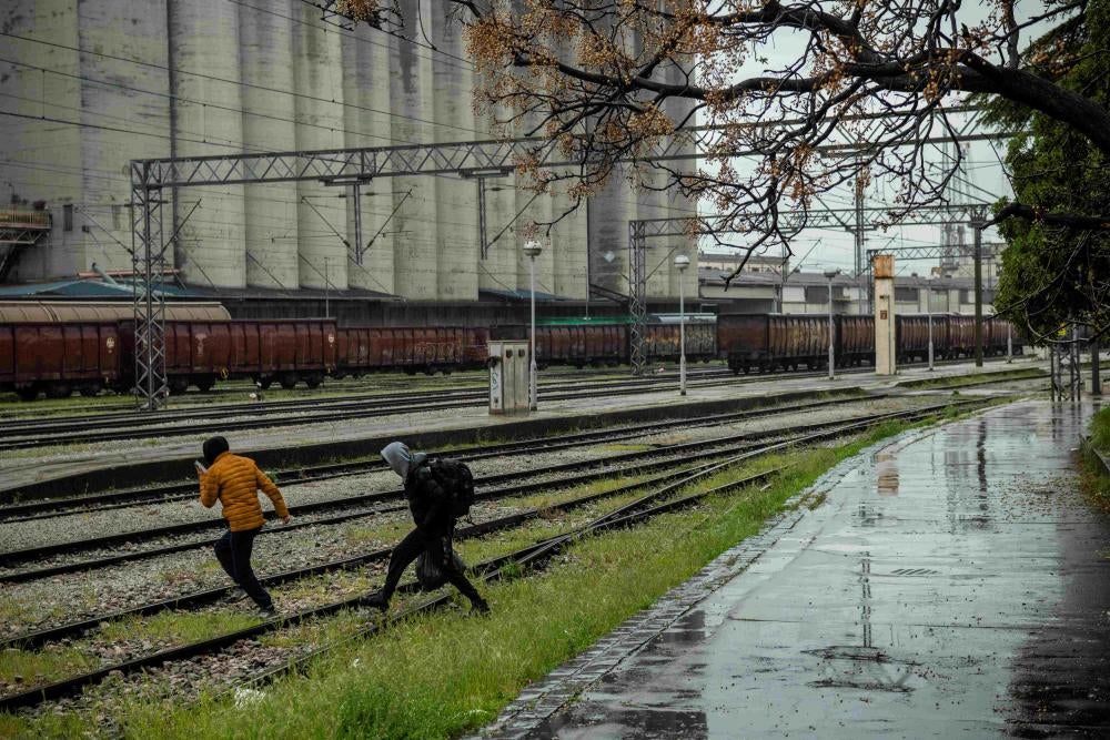 Two men run across train tracks