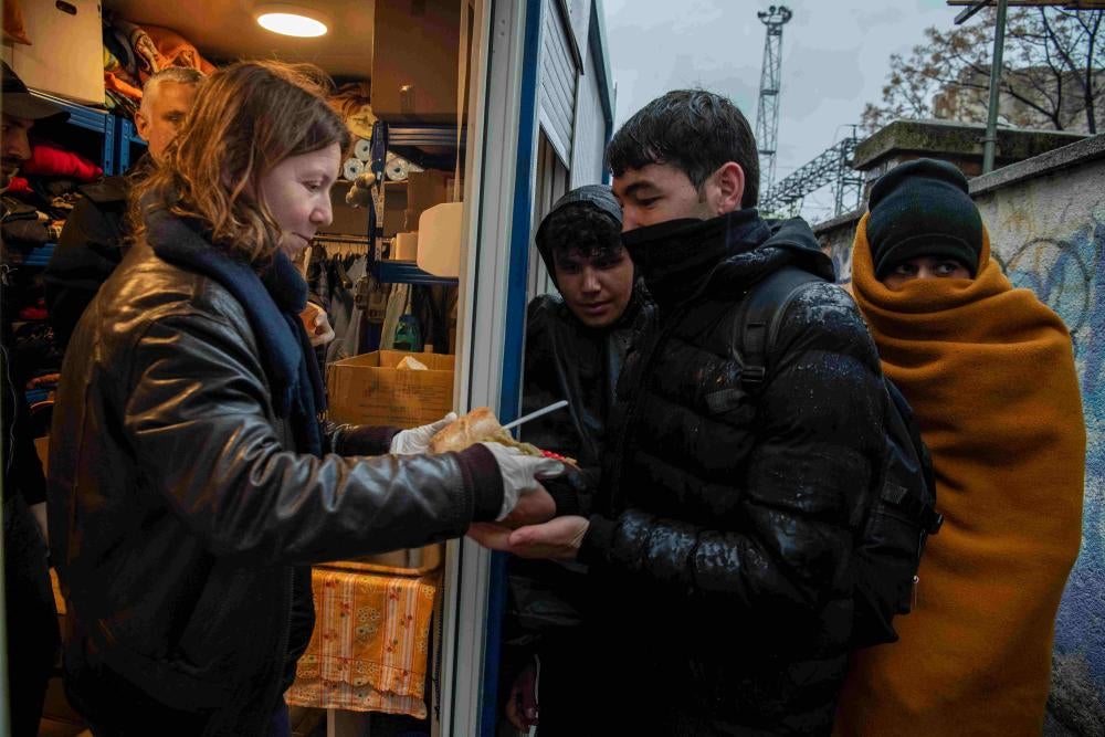 Freiwillige der Caritas und des Jesuiten-Flüchtlingsdienstes verteilen Mahlzeiten an Asylsuchende und Migrant*innen am Bahnhof in Rijeka, Kroatien. 