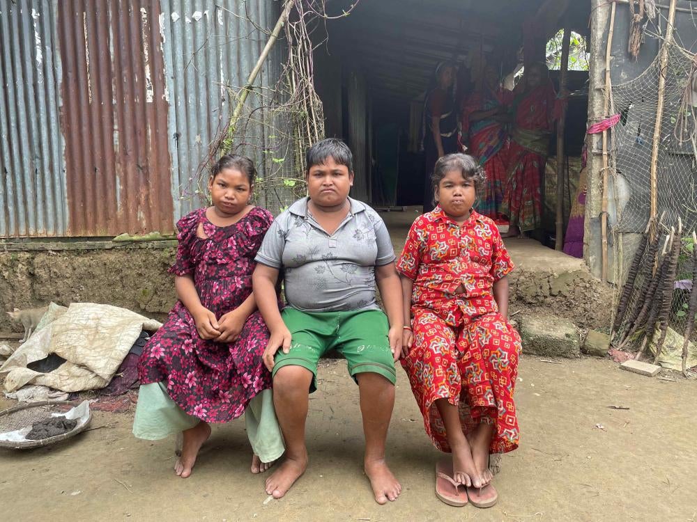 Trois enfants bangladais – Azizul, entouré de ses sœurs Ramina et Hamida – photographiés à Tahirpur, dans le district de Sunamganj. Atteints de handicaps intellectuels et physiques, ils vivent avec leur mère et une autre sœur. Leur frère aîné est décédé lors des inondations de juin 2022.