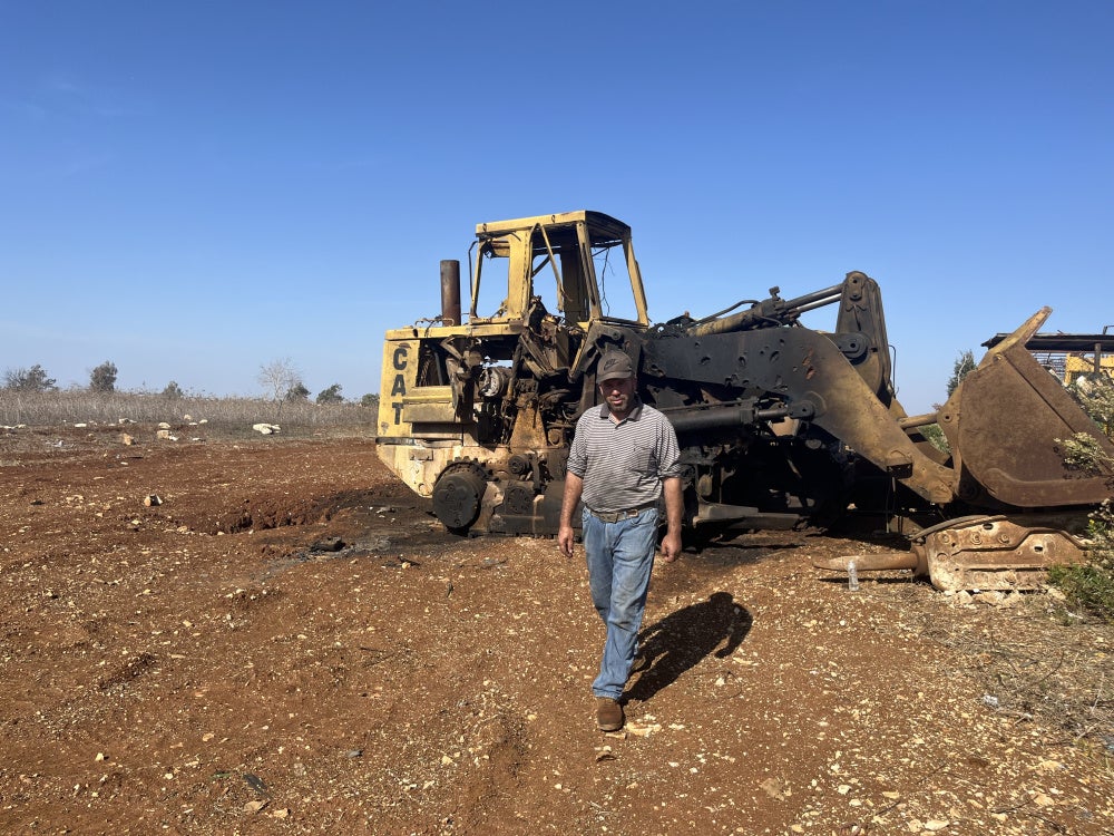 Ibrahim Karim, standing in front of one of the damaged bulldozers from Israeli strikes on August 6, 2025 on Deir Seryan, southern Lebanon.