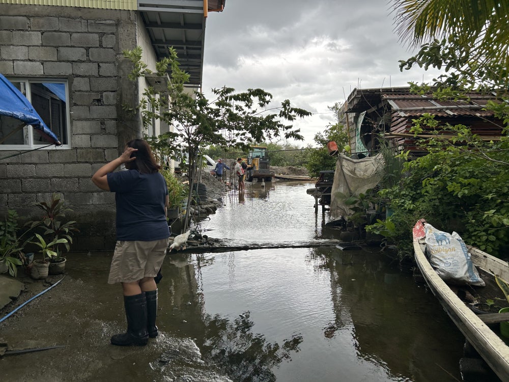 Residents like Evangeline Bansil have a pair of rain boots for daily wear due to flooding at the Pulo relocation site, July 13, 2026.