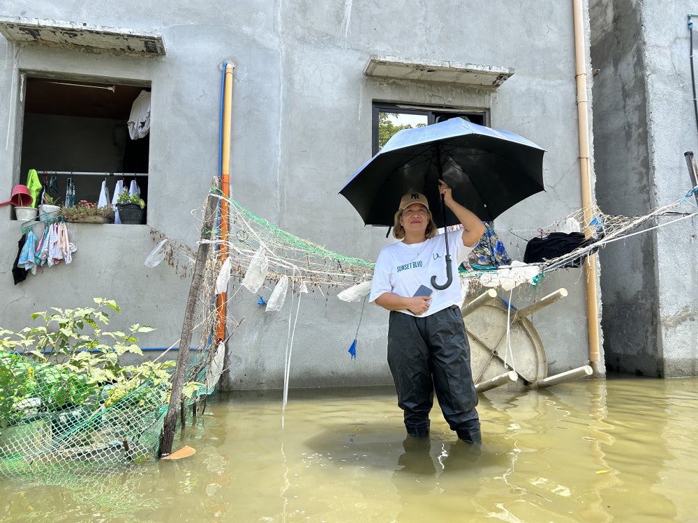 Maria Luz Suñga stands in front of her home at the flooded Pulo relocation site, July 14, 2026.