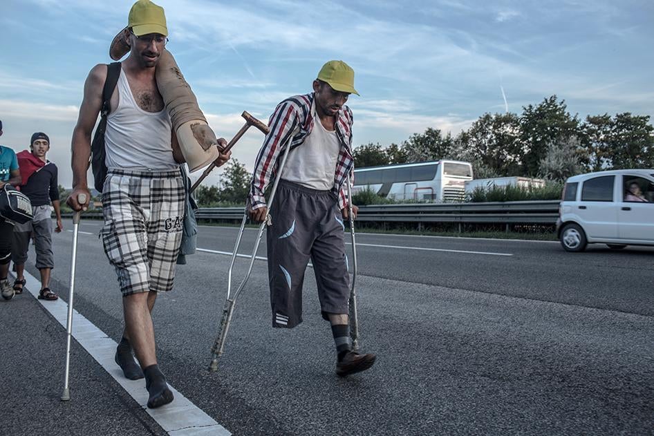 Deux réfugiés syriens marchent sur l’autoroute M2 reliant Budapest et Vienne, en direction de Vienne, le 4 septembre 2015, suite au refus des autorités hongroises de permettre à leur groupe de monter à bord de trains à destination de l’Allemagne. L’homme 