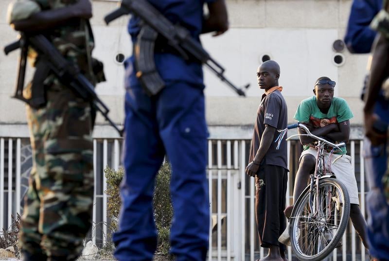 Des badauds regardent des policiers et des militaires qui gardent un bureau de vote dans la capitale du Burundi, Bujumbura, pendant les élections présidentielles, le 21 juillet 2015.