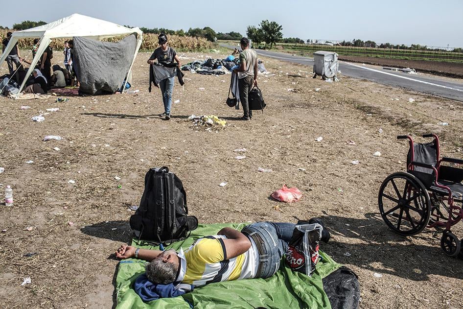 A man rests on the ground in a transit camp in Röszke, Hungary after crossing the border from Serbia. September 3, 2015. 