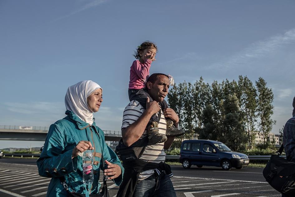 A Syrian refugee carries the daughter of a friend, her mother walking next to him, on the Hungarian M1 highway near Budapest, Hungary on September 4, 2015.