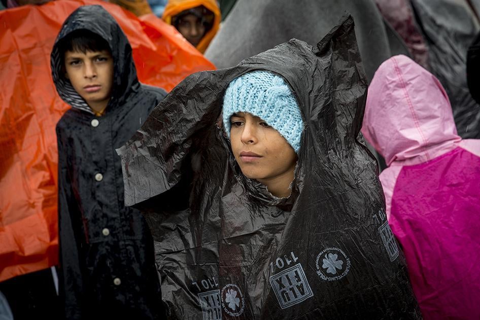 Children from Afghanistan wait in the rain at a collection point in Roszke, Hungary where they will board buses and be taken to detention centers for processing.  September 10, 2015. 