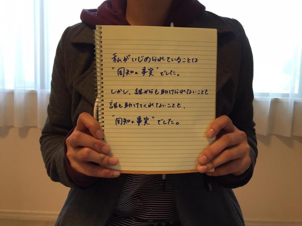 Une Japonaise de 20 ans qui était victime d’intimidation de la part de ses camarades de classe dans une école de l’enseignement secondaire tient un cahier sur lequel est écrit le message suivant : « Tout le monde savait que j’étais victime d’intimidation.