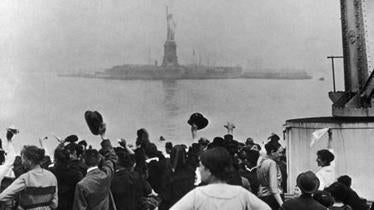 A group of migrants catch their first glimpse of the Statue of Liberty and Ellis Island.
