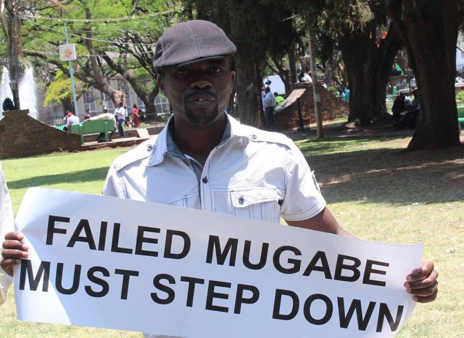 Itai Dzamara stands in Harare's Africa Unity Square, holding a banner that calls on President Robert Mugabe to step down.