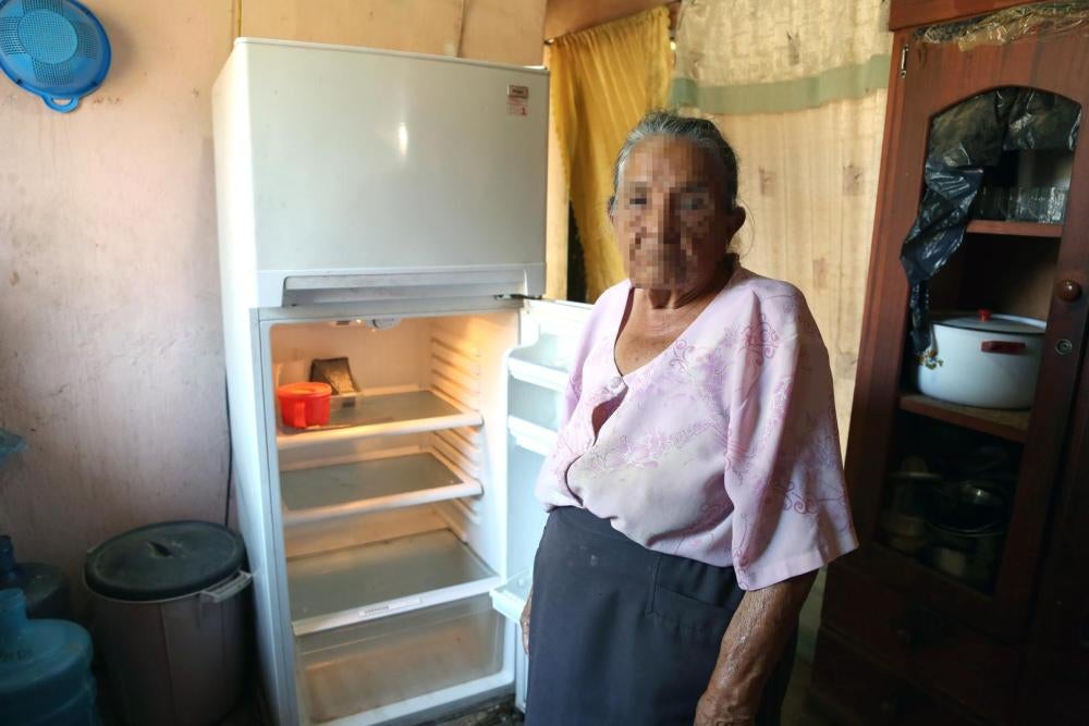An 80-year-old woman shows her fridge, nearly empty, in Zulia State, June 2016. 