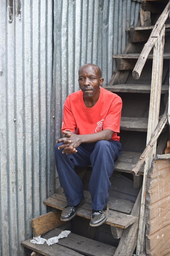 John K., 48, sits at a stair case in a house in Kibera slum.