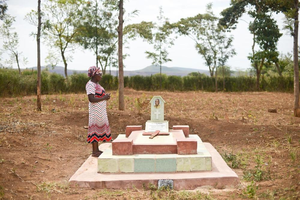 Sinapei  P., 62, stands at her husband’s grave at their home in Rift Valley region. 