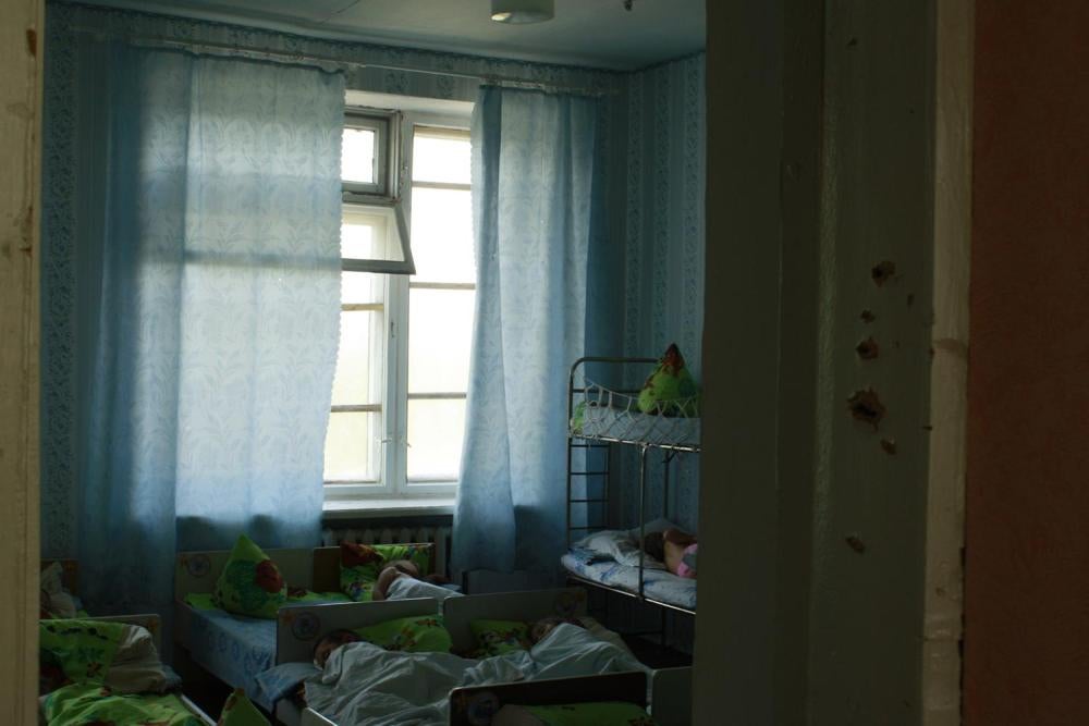 Діти сплять у дитячому садку № 3 в м. Іловайськ, який серйозно постраждав у ході бойових дій у серпні 2014 року. Під час візиту Human Rights Watch у вересні 2015 року більшість вікон були вибиті, а всередині на дверних рамах та стінах були сліди шрапнелі.