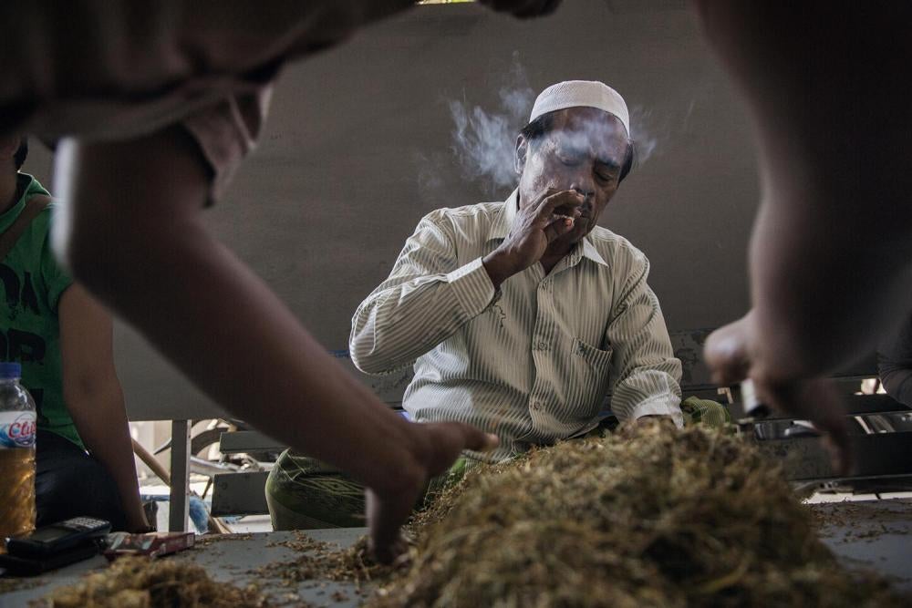Seorang pedagang menilai kualitas tembakau yang didapatkannya dari penjual lain di satu gudang dekat Sumenep, Jawa Timur. Dia mengatakan dia mendapatkan tembakau dari ratusan petani dan pedagang tembakau, lantas menjualnya ke satu pabrik rokok yang dimili
