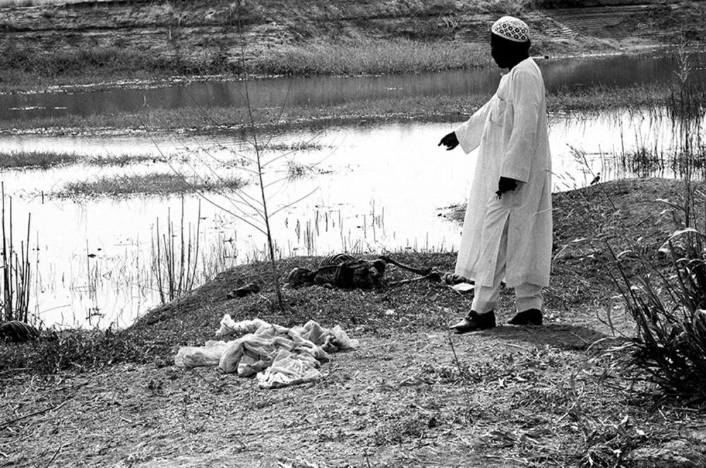 Un habitant de N'Djaména montre un cadavre à proximité du fleuve Chari, à quelques mètres du quartier-général des FAN de Hissène Habré. La photo a été prise le jour même du départ de Hissène Habré, le 15 décembre 1980.