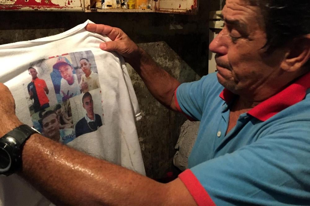 Jorge Augusto Nieira chora quando olha para a camisa com a fotografia dos cinco amigos mortos pela policia em 28 de novembro de 2015. Um deles era seu enteado, Cleiton Corrêa de Souza, de 18 anos. 