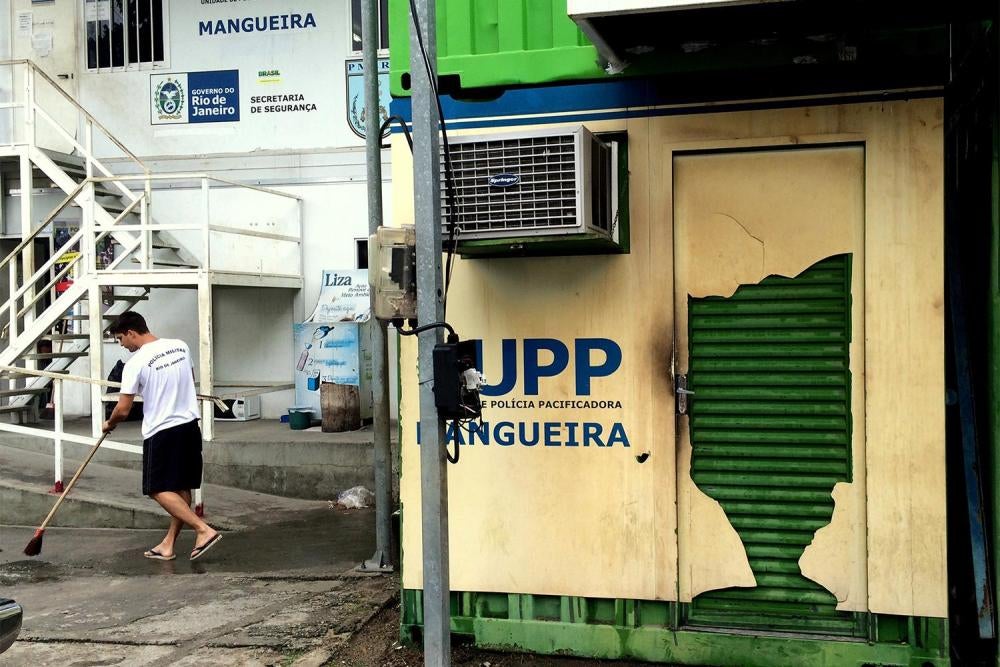 Um policial militar limpa o entorno da Unidade de Polícia Pacificadora (UPP) da favela da Mangueira em 14 de janeiro de 2016. A UPP é feita com contêineres de metal. 