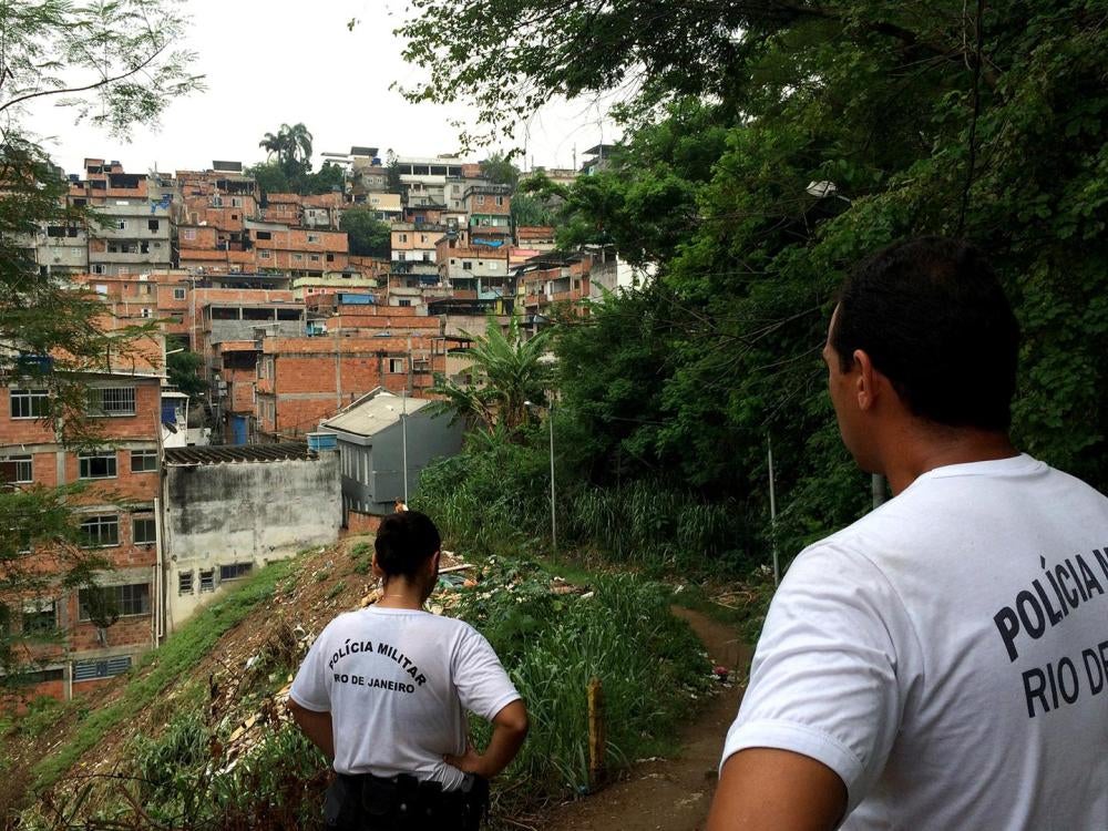 Military police officers Roberta Moreira and Wallace Justo walk through one of the trails at Mangueira favela on January 14, 2016. Members of the local Pacifying Police Unit (UPP), they carry out social projects with children to try to gain the