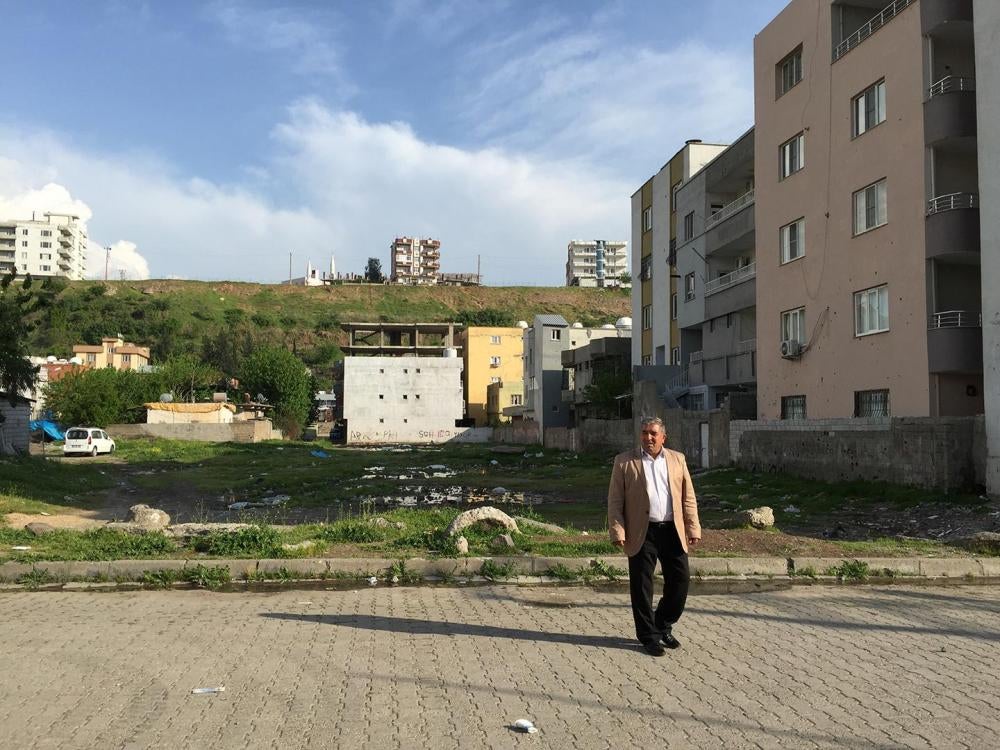 Abdurrahman İnce stands in the place where his father Ramazan İnce, 82, was shot as he attempted to carry his great granddaughter Miray İnce, 3 months, to an ambulance.  The family believe that a military sniper positioned on a high building or on the hil