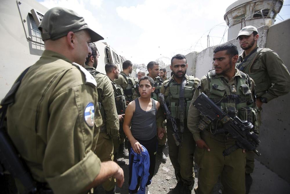  Des soldats israéliens détiennent un garçon palestinien accusé d’avoir jeté des pierres dans la ville de Halhul, en Cisjordanie.