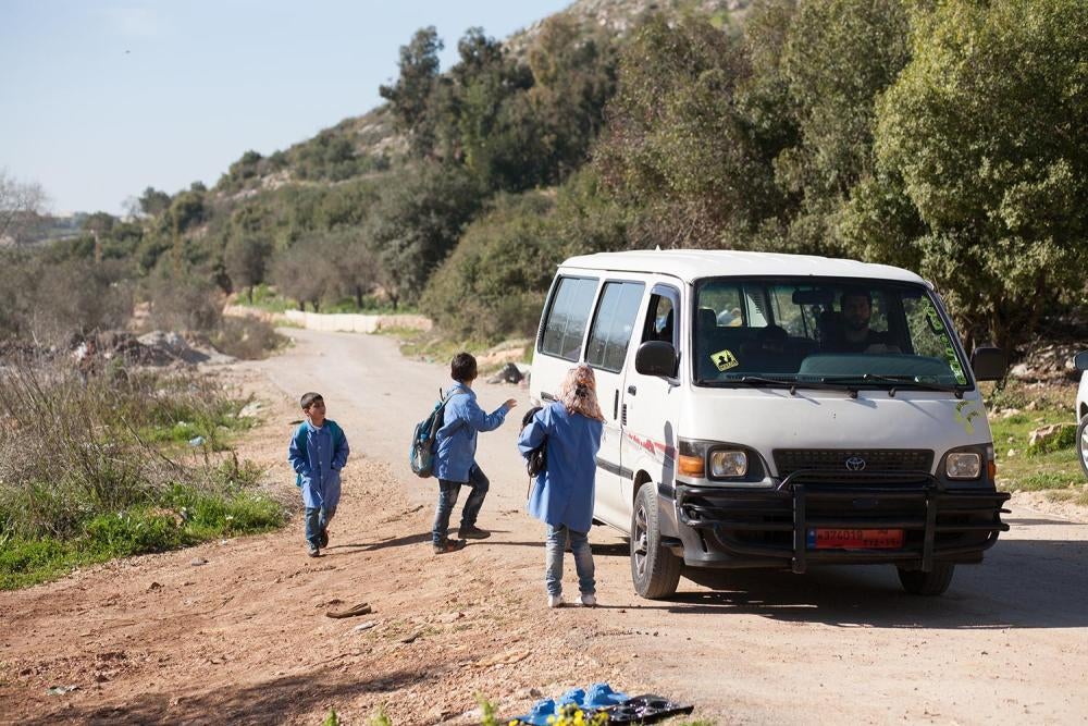 أطفال سوريون يصعدون على متن حافلة مدرسية في مخيم غير رسمي في جبل لبنان.