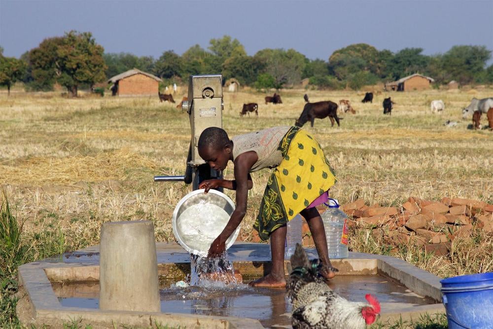 Une jeune fille malawienne lave un récipient à un trou de forage près de la mine de charbon d’Eland à Mwabulambo, dans le district de Karonga, au Malawi. Les femmes et les filles à qui incombe en grande partie la tâche d’approvisionnement en eau ont souve
