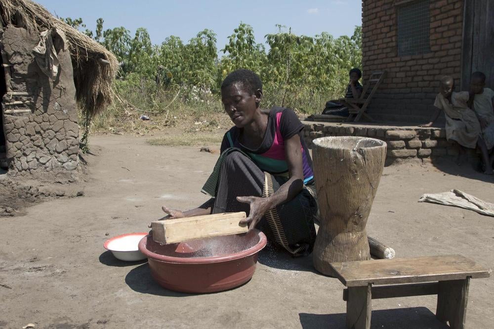 Beatrice N., processing cassava in front of her house in Mwabulambo near an abandoned coal mine. 