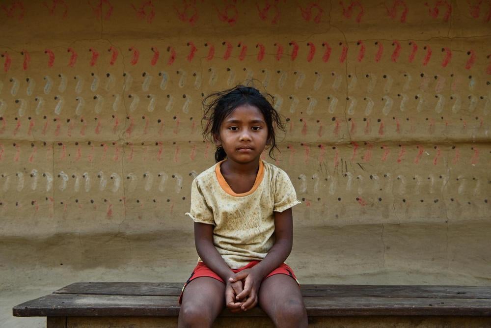 Une fillette népalaise âgée de cinq ans, assise sur un banc de son école. Au Népal, l'éducation fournit une certaine protection contre les mariages précoces, les filles qui vont à l'école étant moins susceptibles de devoir se marier avant d’être majeure. 