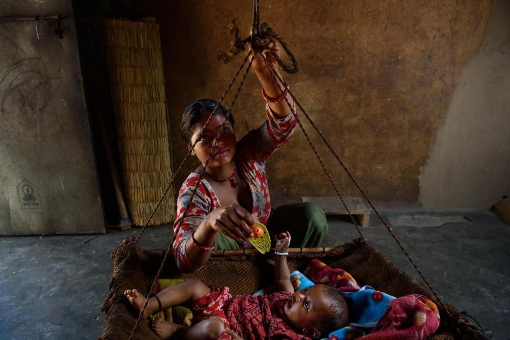 Sarita M., une jeune Népalaise de 17 ans ayant épousé deux ans auparavant un homme de 18 ans qui travaille aujourd’hui comme ouvrier en Inde, joue avec sa fille dans une pièce de sa maison à Chitwan, au Népal. 12 avril 2016.