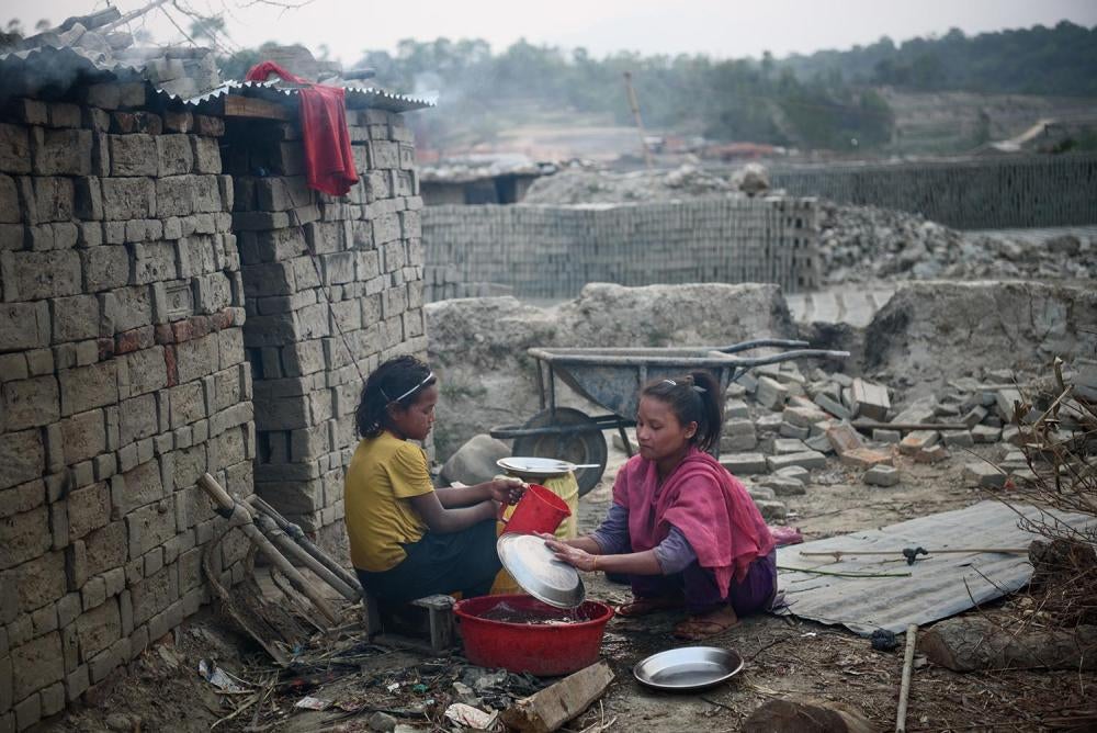 Deux jeunes filles népalaises – Selina, 9 ans, et Bipana, 11 ans – font la vaisselle dans la cour d’une briqueterie où elles travaillent pour aider leurs familles, à Lalitpur, dans le centre du pays.