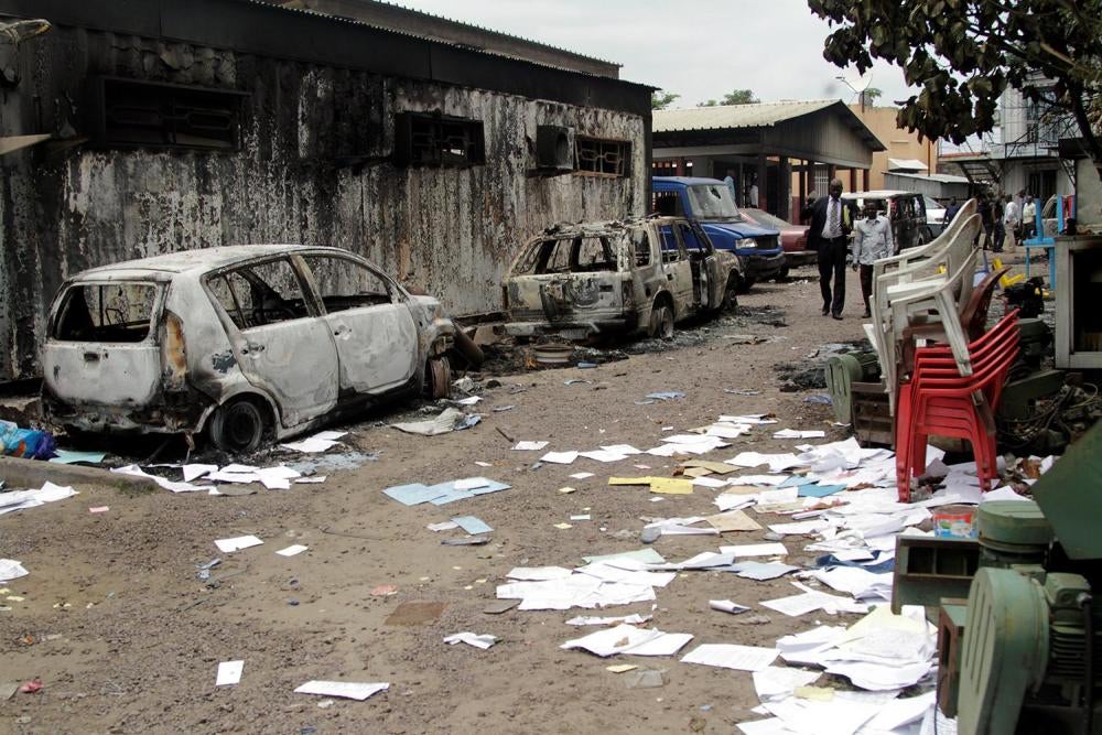 Des habitants passent à côté d'une maison et de véhicules brûlés lors de manifestations antigouvernementales appelant le Président Joseph Kabila à quitter ses fonctions, à Kinshasa, en RD Congo, le 21 septembre 2016.