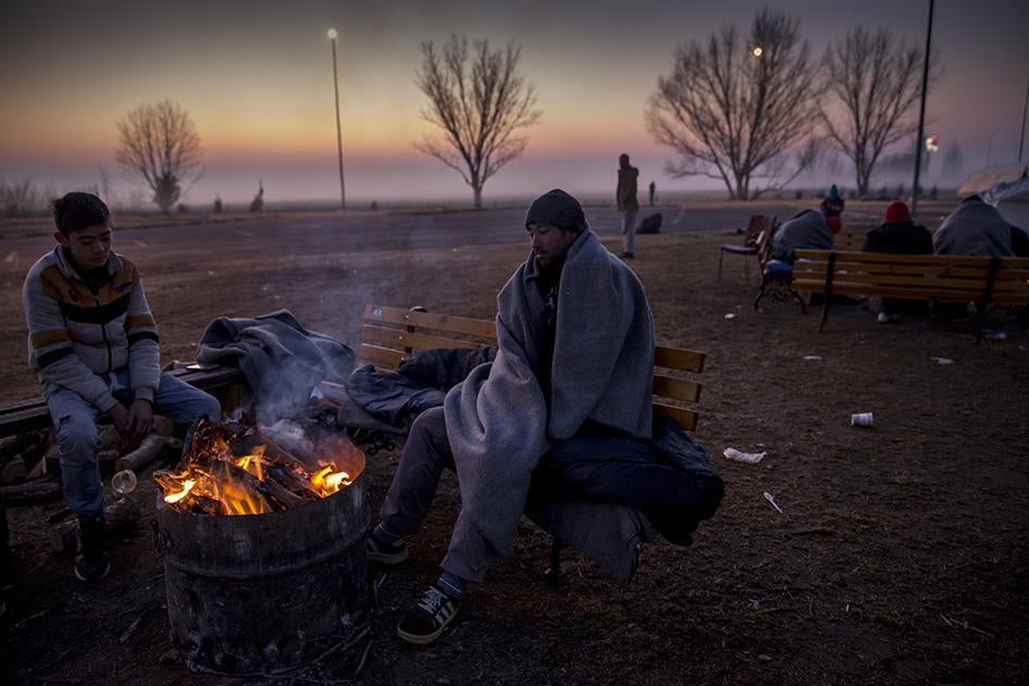 Asylum seekers and migrants, mostly from Syria, Iraq, and Afghanistan, try to warm themselves after a freezing night spent sleeping outside at a petrol station near the Greek border with Macedonia. January 29, 2016.