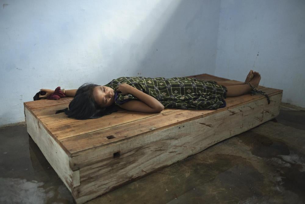 A 24-year-old female resident lies with her wrist and ankle chained to a platform bed at Bina Lestari healing center in Brebes, Central Java. After her husband abandoned her and her 5 year-old daughter to marry someone else, she began to experience depres