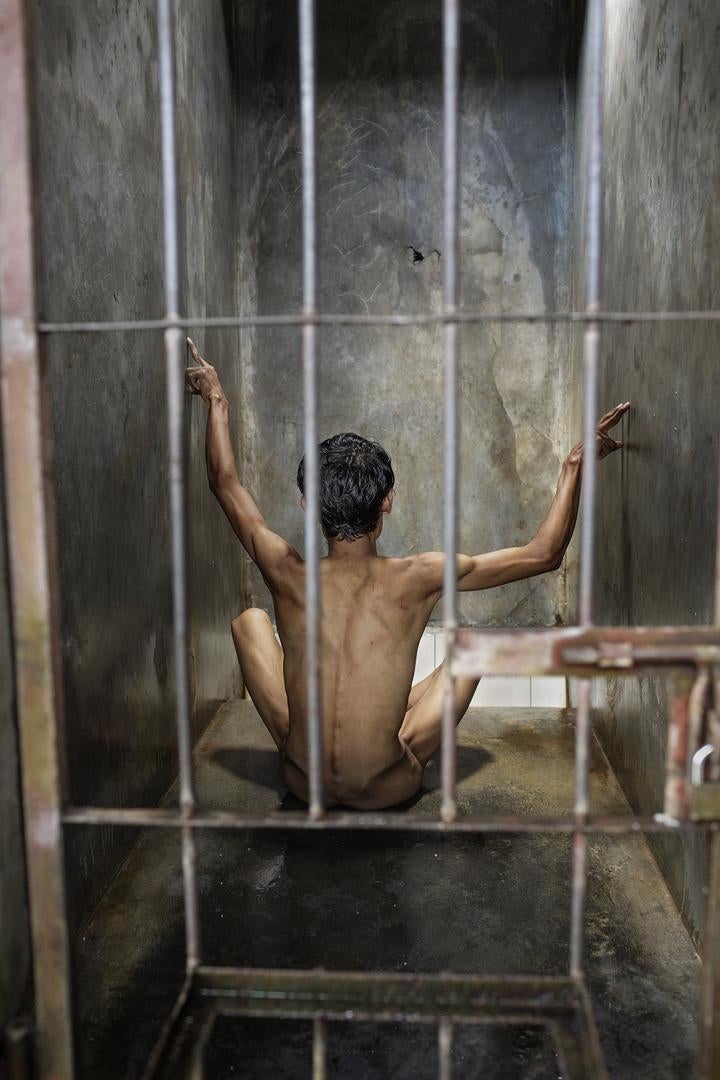Seorang pria menyanyi di selnya, tanganya bergerak dalam tarirumit, di Pengobatan Alternatif Jasono, sebuah pusat pengobatantradisional di Cilacap, Jawa Tengah.  