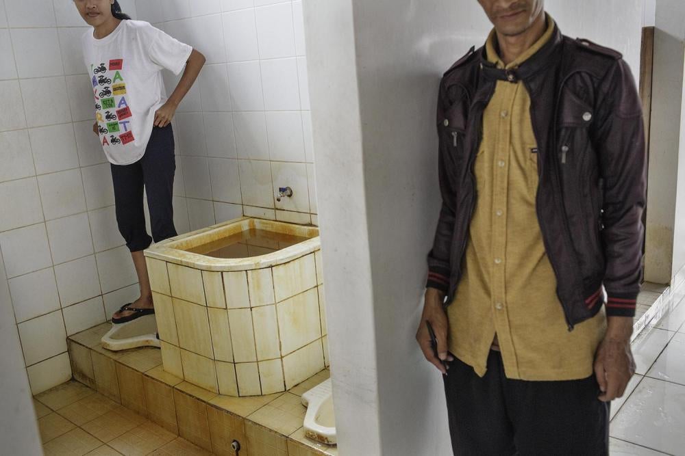 A woman resident in the female section of Galuh Rehabilitation Center in Bekasi waits for a male staff member to leave before she uses the toilet. Female residents have no privacy and are at heightened risk of sexual violence as the toilets have no doors 