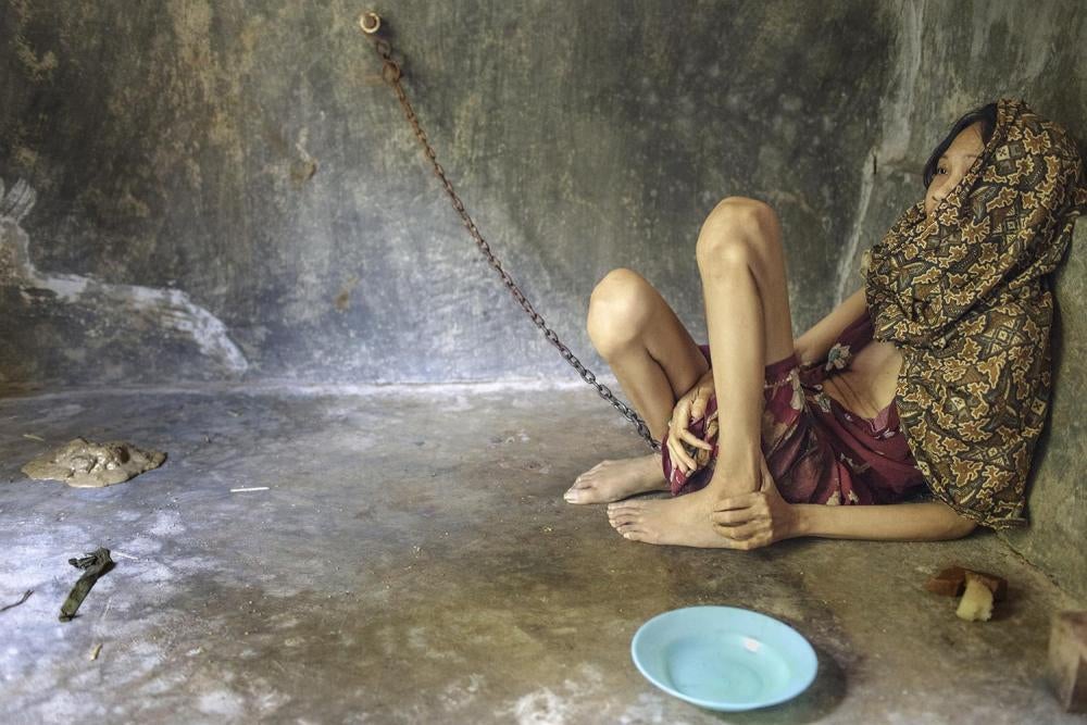A woman chained in a room built behind her family home in Ponorogo, East Java. She is forced to eat, sleep, and defecate in this room.