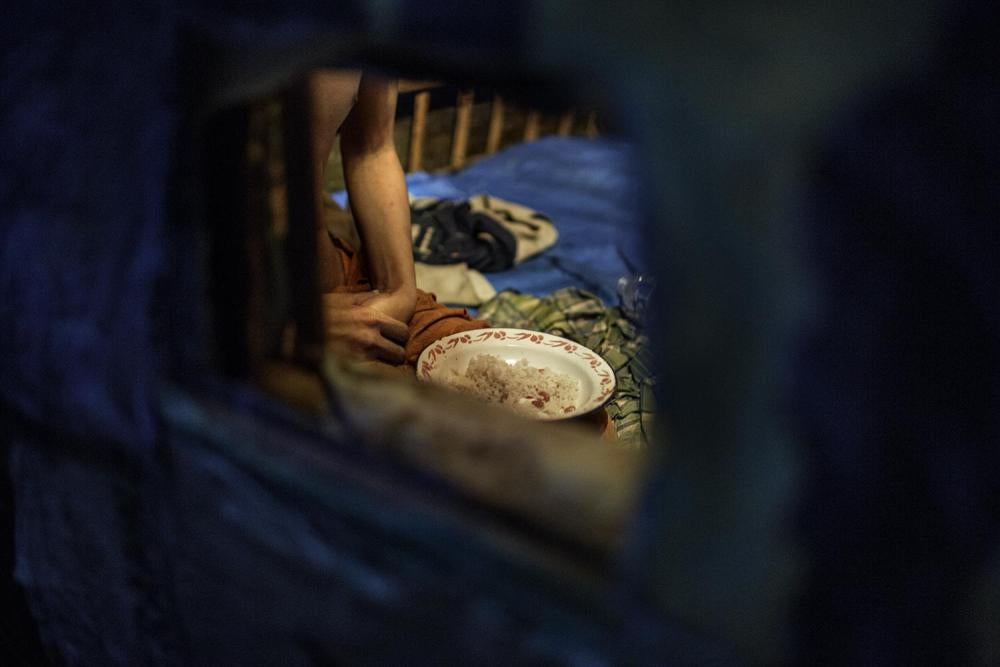 Ekram, seorang pria dengan disabilitas psikososial, makan malamdi gudang di luar rumah keluarga di mana ia disekap. Keluargamemberi makanan dan air lewat lubang kecil di dalam gudang. © 2016 Andrea Star Reese untuk Human Rights Watch 