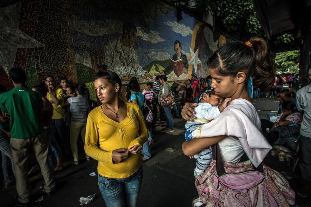 Jailimar Laverde, 17, (left) and Yanny Trejo, 19, (right) wait in a queue of hundreds of people outside a supermarket in Caracas rumored to have received a shipment of corn flour and butter, March 19, 2016.