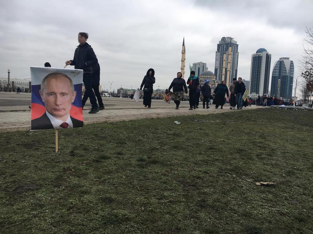 Des personnes ayant participé à Grozny, la capitale de la Tchétchénie dans le sud de la Russie, à une manifestation de soutien au dirigeant tchétchène Ramzan Kadyrov organisée en janvier 2016 par les autorités, passent devant un portrait du président russ