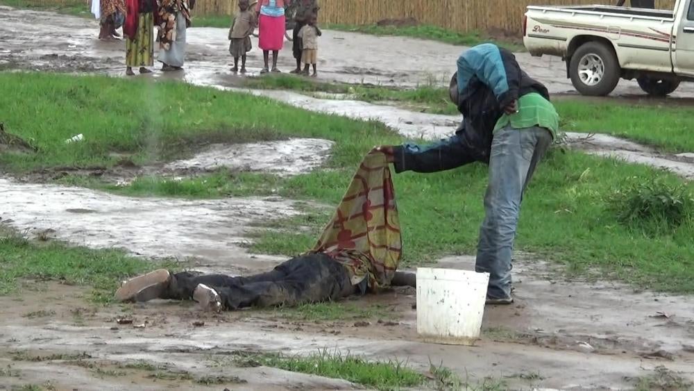 A passer-by lifts a sheet covering the body of a man found decapitated in the Mutakura neighborhood of Bujumbura, November 4, 2015.