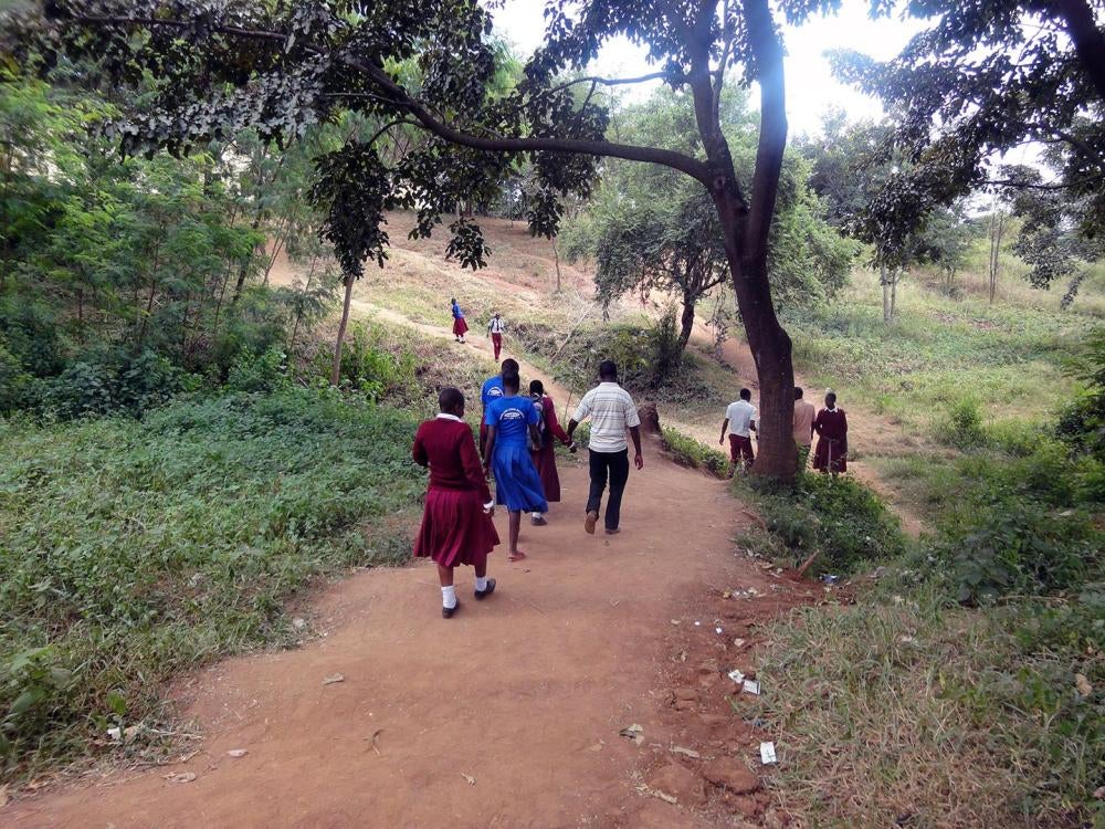 Female students who are blind, are guided down a steep and slippery hill by their teachers. They have to walk through rough terrain to get from their secondary school to their school’s hostel in Mwanza city.