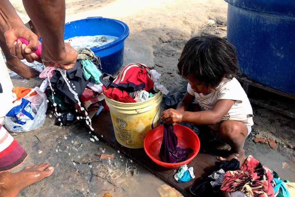 Una niña de la comunidad indígena venezolana Warao juega en un refugio en Boa Vista. El agua que usaban para ducharse y lavar la ropa corre por el suelo, sin canalización. 11 de febrero de 2017. 