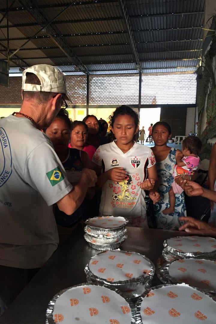Membros da equipe da Fraternidade, uma organização internacional de ajuda humanitária, distribuem refeições em um abrigo em Boa Vista, onde mais de 180 venezuelanos viviam em fevereiro de 2017. 11 de fevereiro de 2017. 