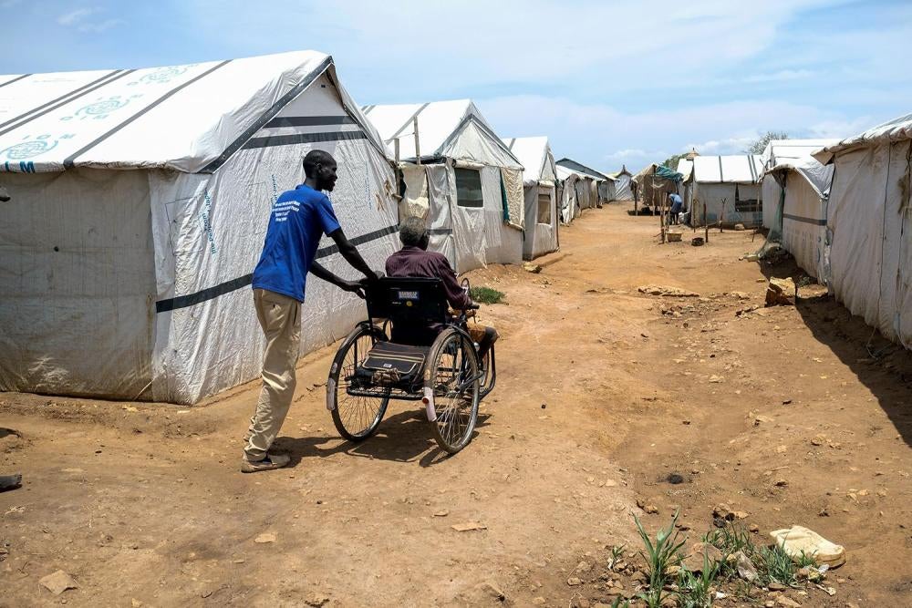 A relative pushes John Biel Dup’s wheelchair through the dirt paths of Protection of Civilians Camp 3 in Juba,. The uneven paths make it difficult for people with physical disabilities to move around the camps..