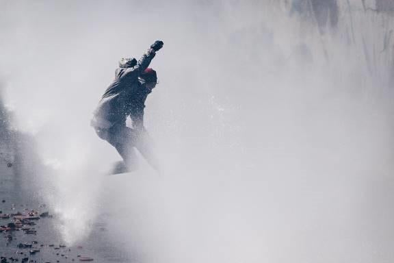 A demonstrator is hit by the jet of a riot police water cannon during an anti-government protest in Caracas, Venezuela. April 6, 2017. 