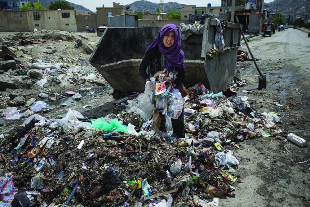 A 10-year-old girl sorts through rubbish to salvage plastic containers that she can sell. 